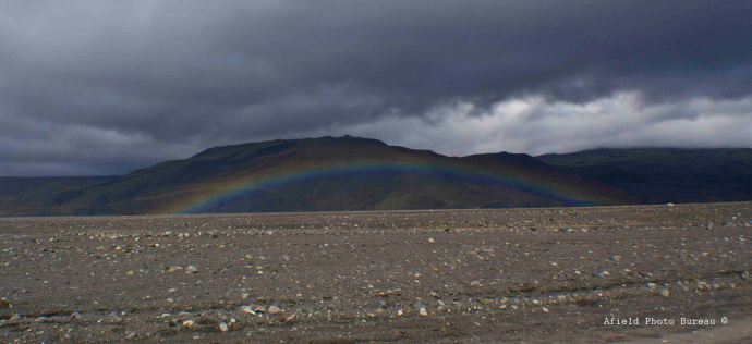A rainbow arching low over the river.